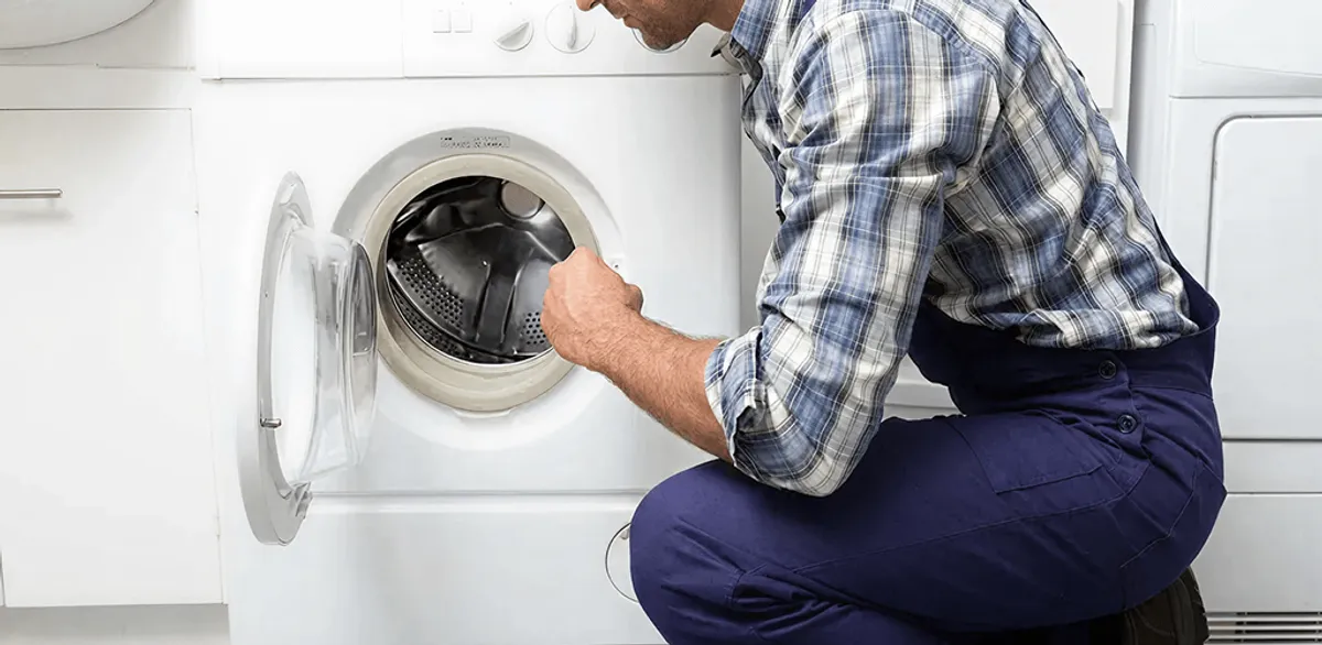 Handyman inspecting a dryer drum and internal parts for repair in Overland Park, KS