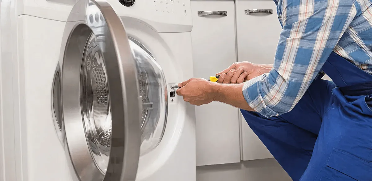 Handyman repairing a clothes dryer and checking electrical connections in Overland Park, KS
